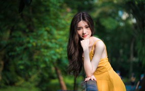 Девушка азиатка с большими карими глазами в желтом платье 