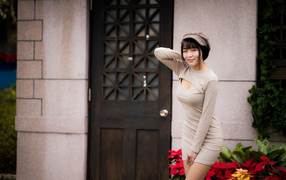 Красивая азиатка в платье стоит у двери 