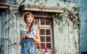 Красивая девушка азиатка в сарафане у старого дома 