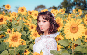 Красивая девушка азиатка в белом платье на поле с подсолнухами