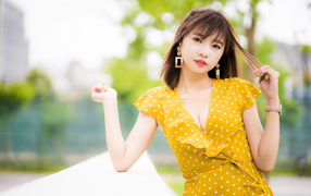 Красивая азиатка в желтом платье в белый горох 