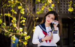 Красивая девушка азиатка в форме с цветами в руках 