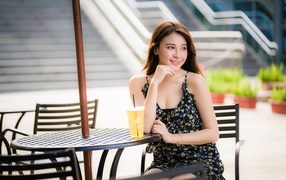 Красивая девушка азиатка сидит за столиком в кафе