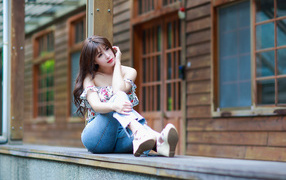 Красивая девушка азиатка сидит у дома