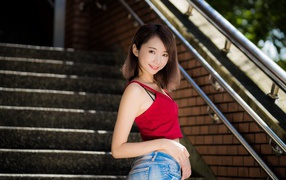 Красивая девушка азиатка стоит на ступенях 