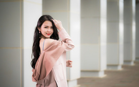 Красивая девушка азиатка с длинными волосами в розовом пальто 