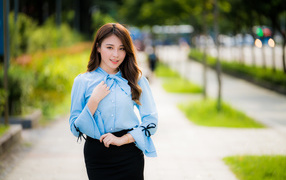 Красивая азиатка в голубой блузке и черной юбке 