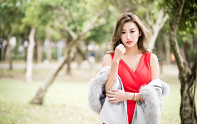 Красивая азиатка в красном платье в парке
