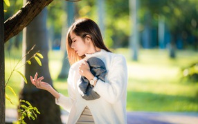 Красивая азиатка в белой кофте в солнечном парке