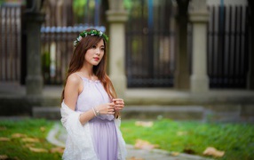 Красивая азиатка в сиреневом платье с венком на голове