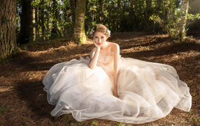 Красивая девушка азиатка в белом свадебном платье сидит на земле