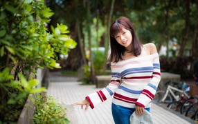 Красивая азиатка в полосатом свитере в парке