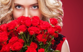 Beautiful blue-eyed blonde with a bouquet of red roses