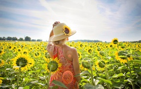 Красивая девушка в шляпке на поле с подсолнухами летом