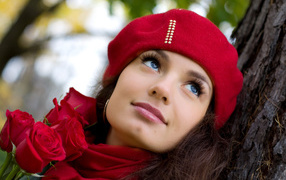 Красивая девушка в красном берете с букетом роз у дерева
