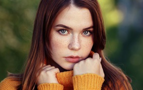 Beautiful girl in a warm sweater with freckles on her face.