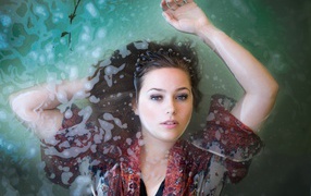 Красивая девушка лежит в одежде в воде 