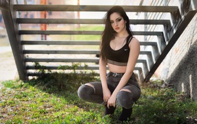 Красивая девушка сидит под лестницей 