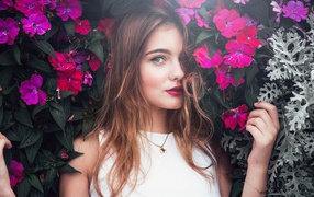 Красивая девушка стоит у зарослей с розовыми цветами