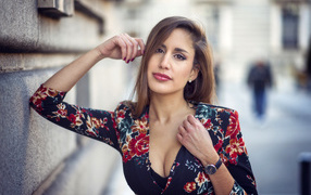 Красивая девушка с часами на руке стоит у стены