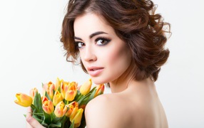 Красивая девушка с прической в букетом тюльпанов в руках на белом фоне
