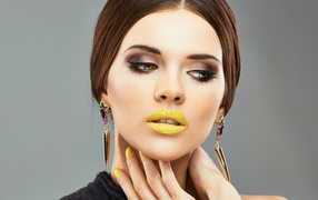 Красивая девушка с дорогими серьгами в ушах на сером фоне