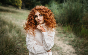 Красивая рыжеволосая девушка в белом свитере с рисунками из хны на руках