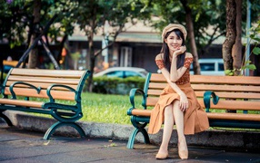 Beautiful smiling asian woman sitting on a bench in a park
