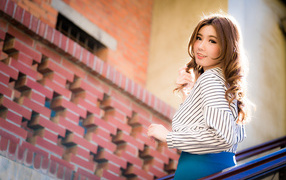 Красивая улыбающаяся азиатка стоит на лестнице 