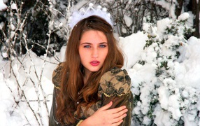 Красивая молодая девушка замерзает у покрытого снегом дерева