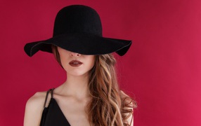 Большая черная шляпа закрывает лицо девушки