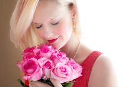 Блондинка с закрытыми глазами нюхает букет роз