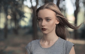 Голубоглазая девушка в серой майке в парке 