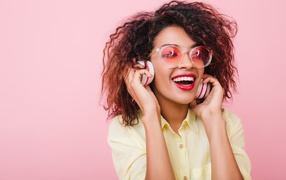 Яркая улыбающаяся девушка слушает музыку в наушниках 