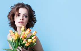 Кареглазая шатенка с букетом тюльпанов на голубом фоне
