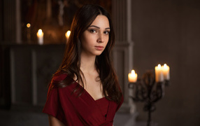 Кареглазая девушка в красном платье в комнате со свечами