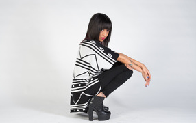 Брюнетка сидит на корточках 