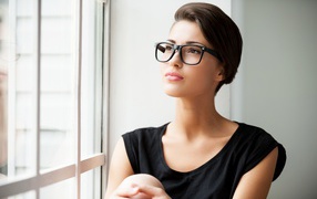 Business girl in glasses sits by the window