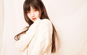 Милая азиатка в белом свитере на розовом фоне