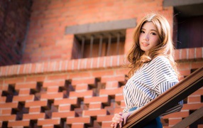 Милая девушка в полосатой рубашке стоит на ступеньках 