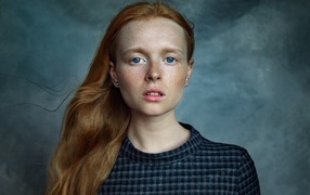 Милая рыжеволосая голубоглазая девушка с веснушками на лице на сером фоне