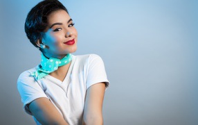 Милая улыбающаяся девушка с шарфом на шее на сером фоне