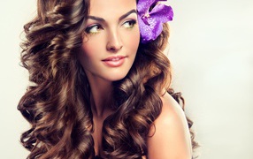 Цветок в красивых длинных волосах молодой девушки