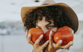 Девушка в шляпе с помидорами в руках 