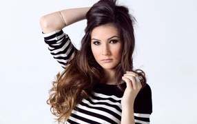 Девушка в полосатом свитере с рукой в волосах на белом фоне