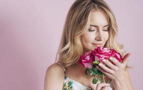 Девушка вдыхает аромат роз  