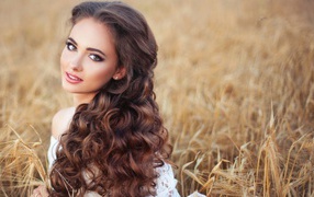 Девушка с красивыми длинными волосами на поле с пшеницей