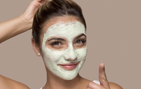 Девушка с завязанными волосами с косметической маской на лице