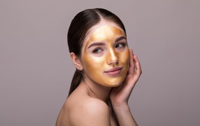 Золотая маска на лице у молодой девушки 