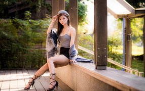 Длинноногая азиатка сидит на окне 